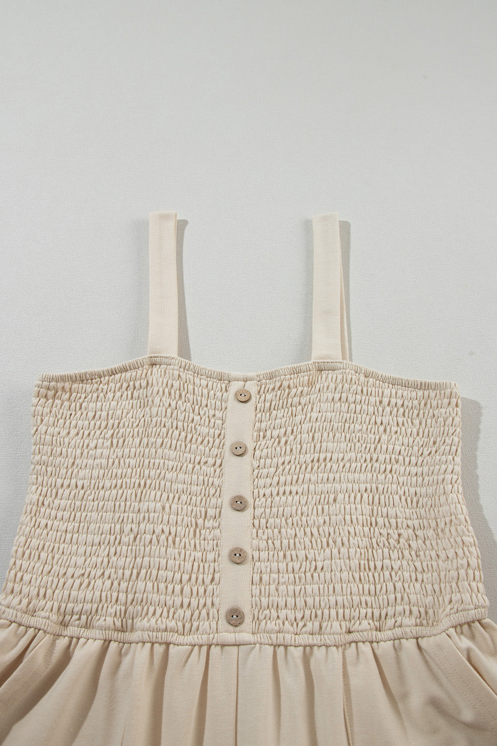 Beige Solid Color Buttons Smocked Sleeveless RomperMaterial:85%Polyester+10%Cotton+5%Elastane

• Its high waist design adds a flattering touch to any silhouette.
• Embrace the versatility of this romper with its sl